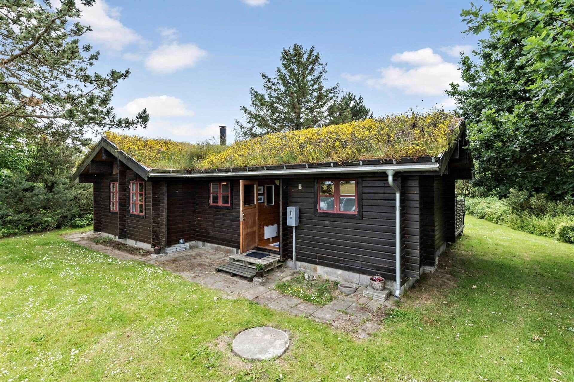 Een houten chalet met een schuin dak, een veranda en een kleine tuin.