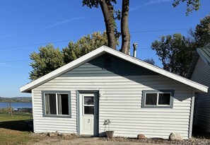 A small, single-story cabin with a door, two windows, and a chimney. - Lake Wisconsin Resort (Poynette)