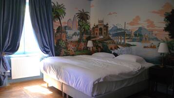 Ein Hotelzimmer mit einem großen Bett, einem Wandgemälde, das eine historische Szene zeigt, einem Fenster mit Vorhängen und einem Heizkörper.