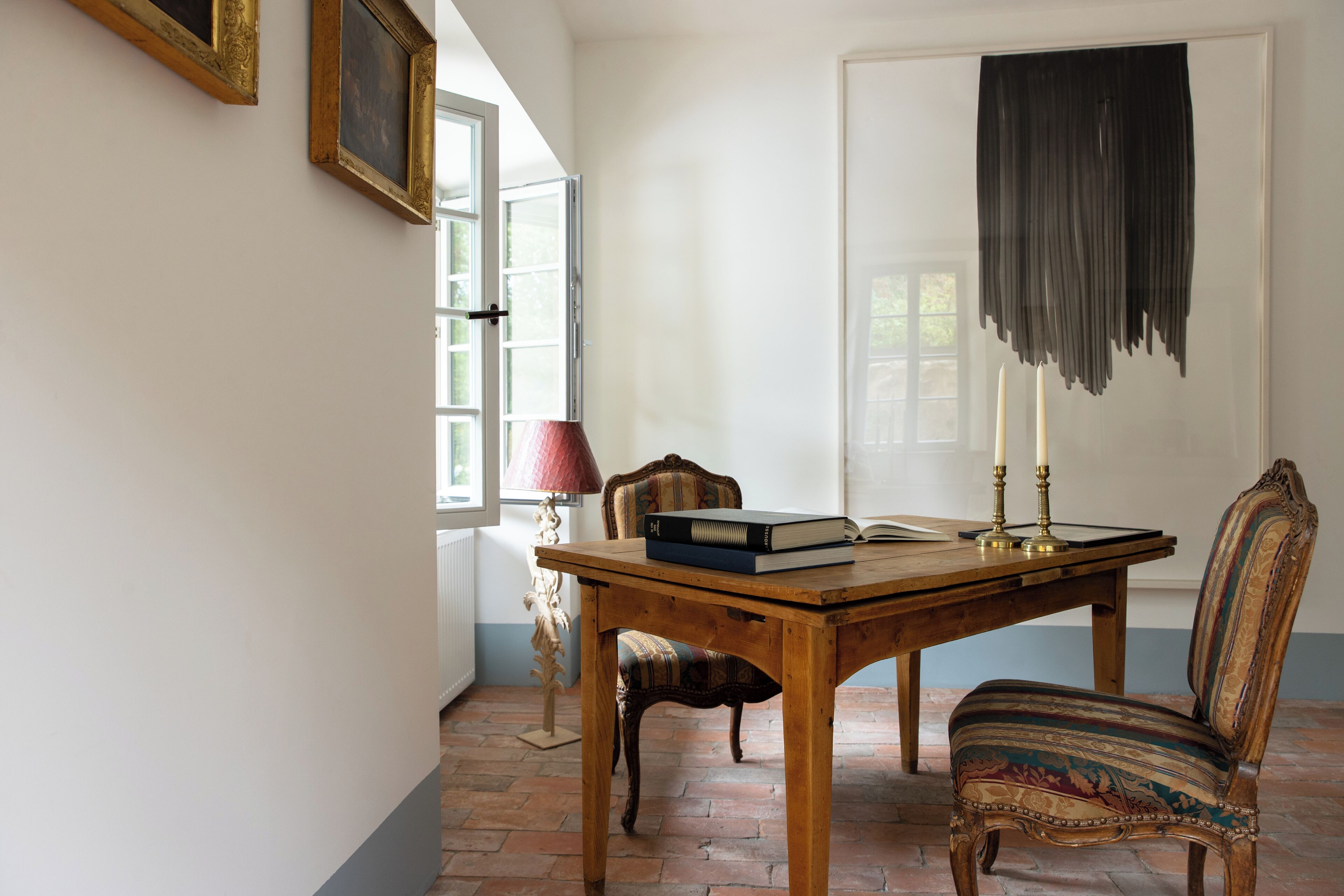 Una habitación con una mesa de madera, una silla, una lámpara y un libro.