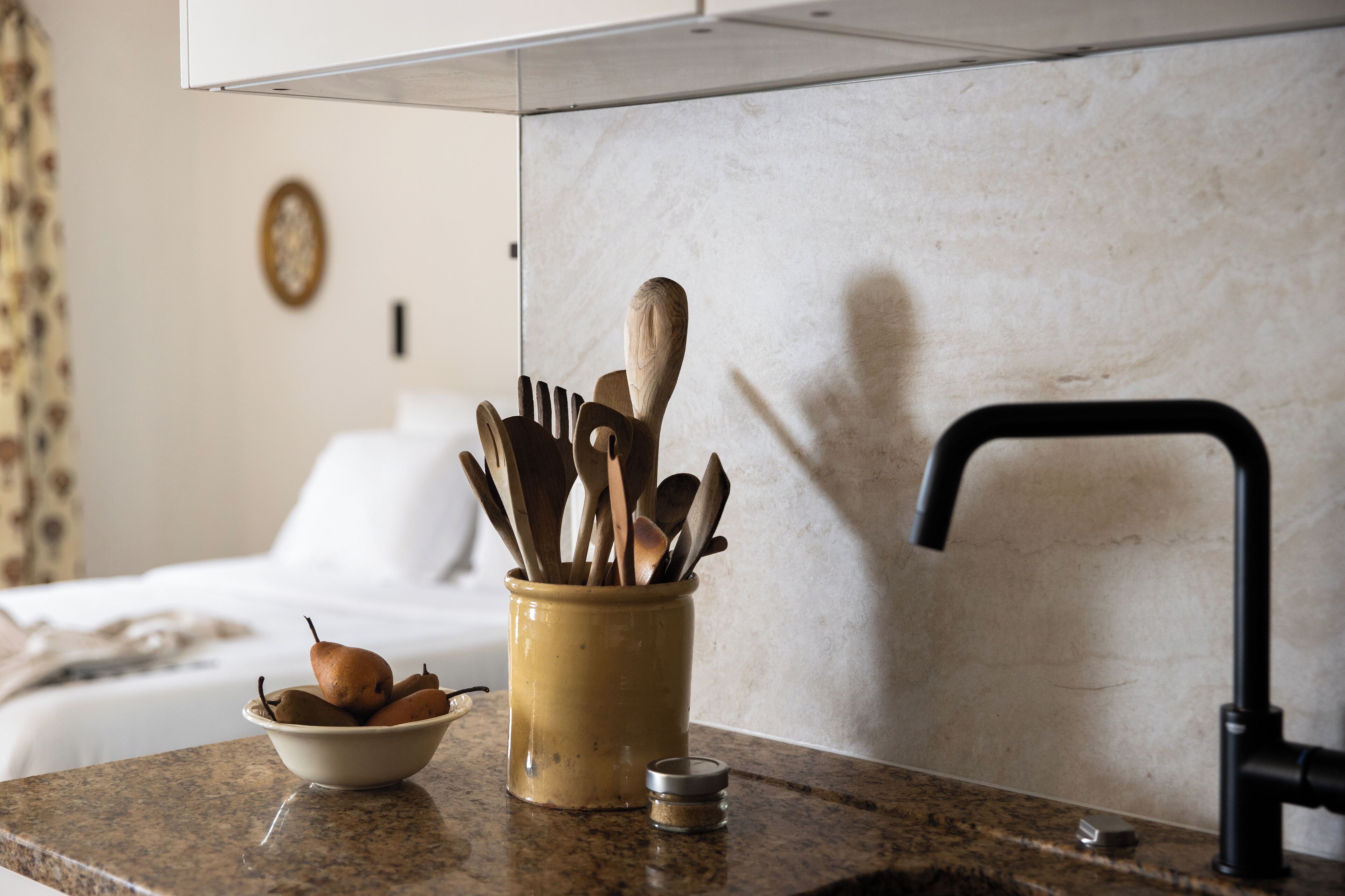 A kitchen counter with a bowl of pears and a utensil holder.
