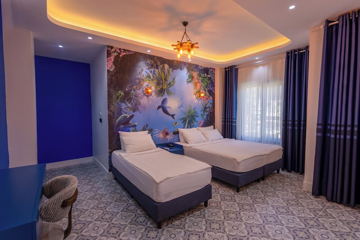 A hotel room with two beds, a mural of marine life on the wall, and a patterned floor.