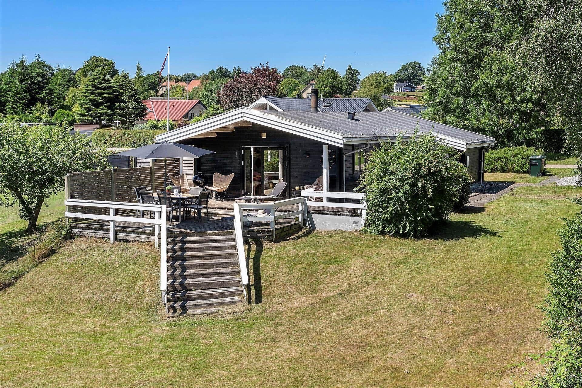 A house with a deck, outdoor seating, and a staircase leading to the entrance.