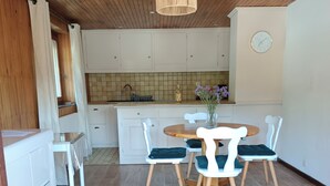 Una cocina moderna con armarios blancos, techo de madera y una mesa redonda de comedor con sillas.
