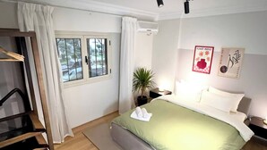 A bedroom with a bed, a nightstand, a potted plant, and a window with curtains. - GroundFloor Serenity (Cairo Governorate)