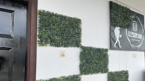 Un mur orné d’un motif à carreaux de feuillage vert et d’une enseigne indiquant « Elysium Inn ».