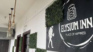 L’entrée d’un hôtel, avec une enseigne indiquant « Elysium Inn » et « Lieu de bonheur ».