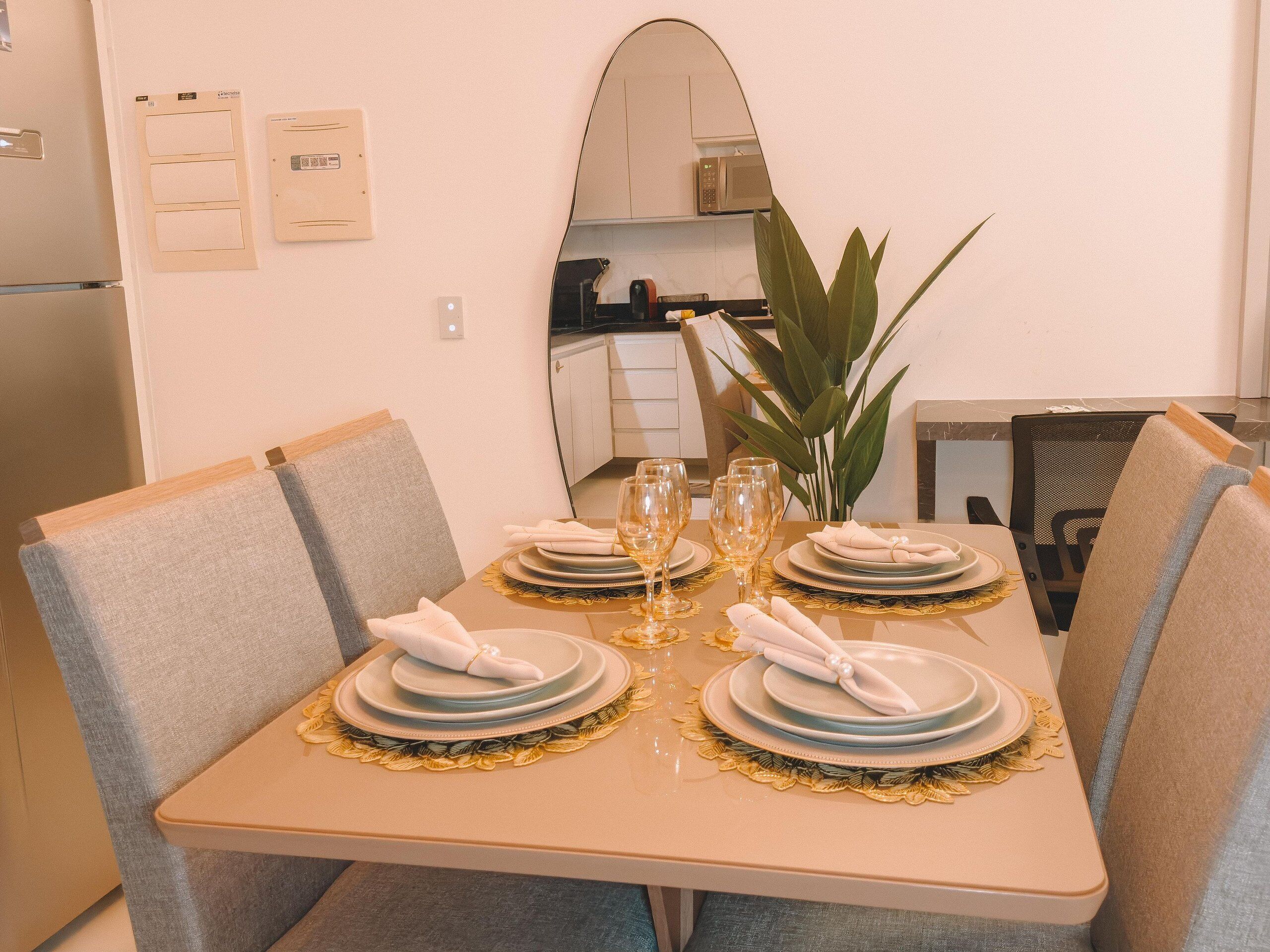 A dining table set with plates, glasses, and napkins, surrounded by chairs.