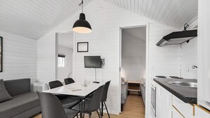 A modern kitchen with white cabinetry, a black countertop, and a hanging pendant light. - 5 Person Holiday Park Home in Holbaek (Holbaek)