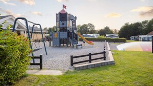 A playground with a castle-like structure, a slide, and a fenced area. - 5 Person Holiday Park Home in Holbaek (Holbaek)