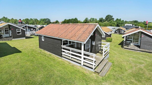 A row of small, single-story cabins with a metal roof, each featuring a porch and a small deck. - 5 Person Holiday Park Home in Holbaek (Holbaek)