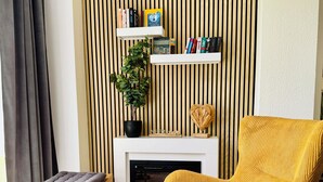 A living room with a fireplace, a yellow armchair, a bench, and a small table with wine glasses. - Exclusive flat, front row, directly on the beach, 200m from the pier (Binz)