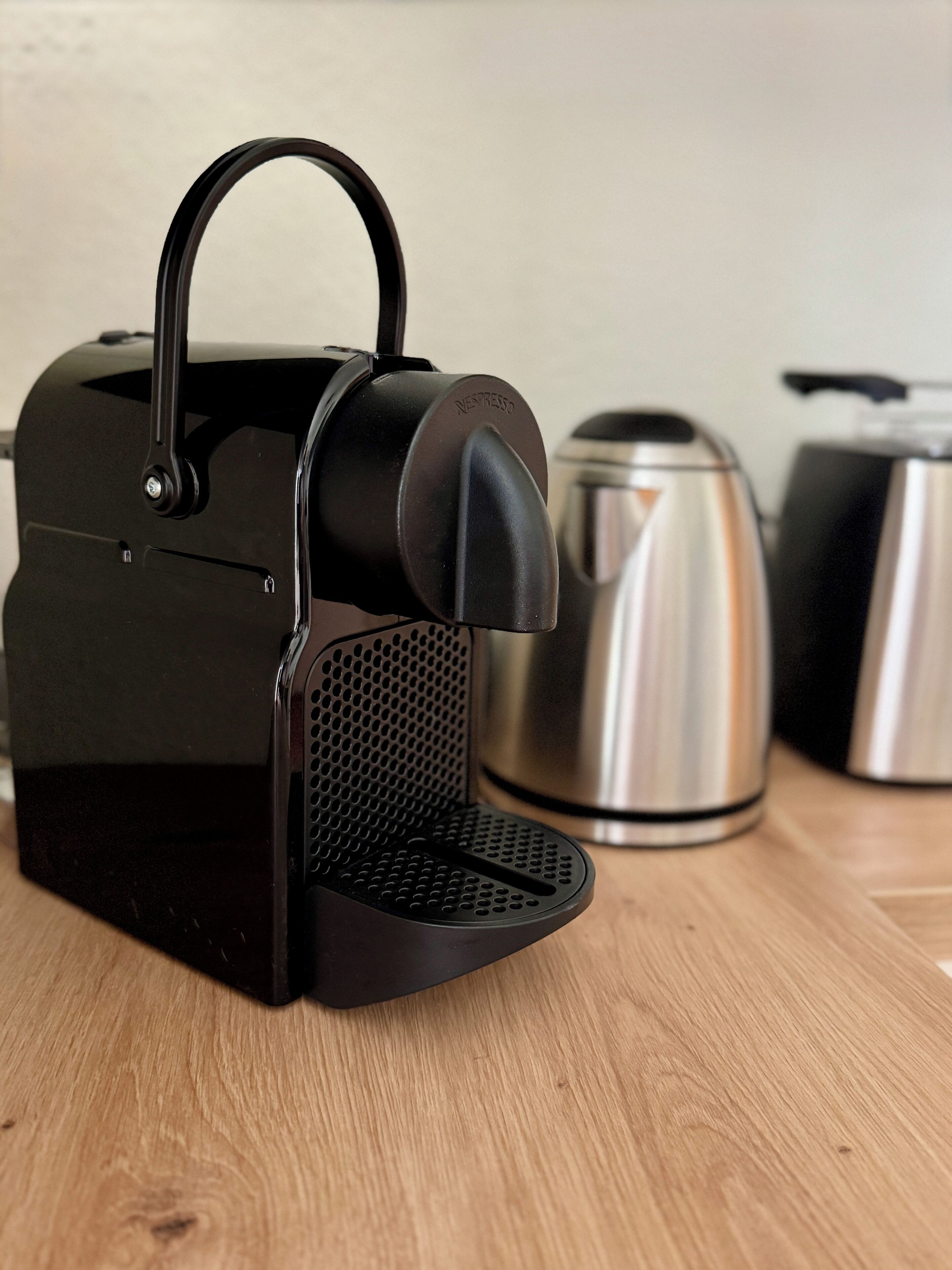 A black espresso machine with a handle and a drip tray on a wooden surface.