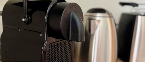 A black espresso machine with a handle and a drip tray on a wooden surface.