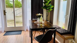 A dining area with a wooden table, black chairs, a cushioned bench, a potted plant, and a bottle of wine. - Exclusive flat, front row, directly on the beach, 200m from the pier (Binz)