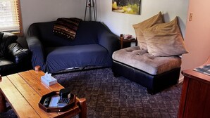 Un salon chaleureux avec un canapé bleu foncé, une table basse en bois et un tableau sur le thème des ours accroché au mur.