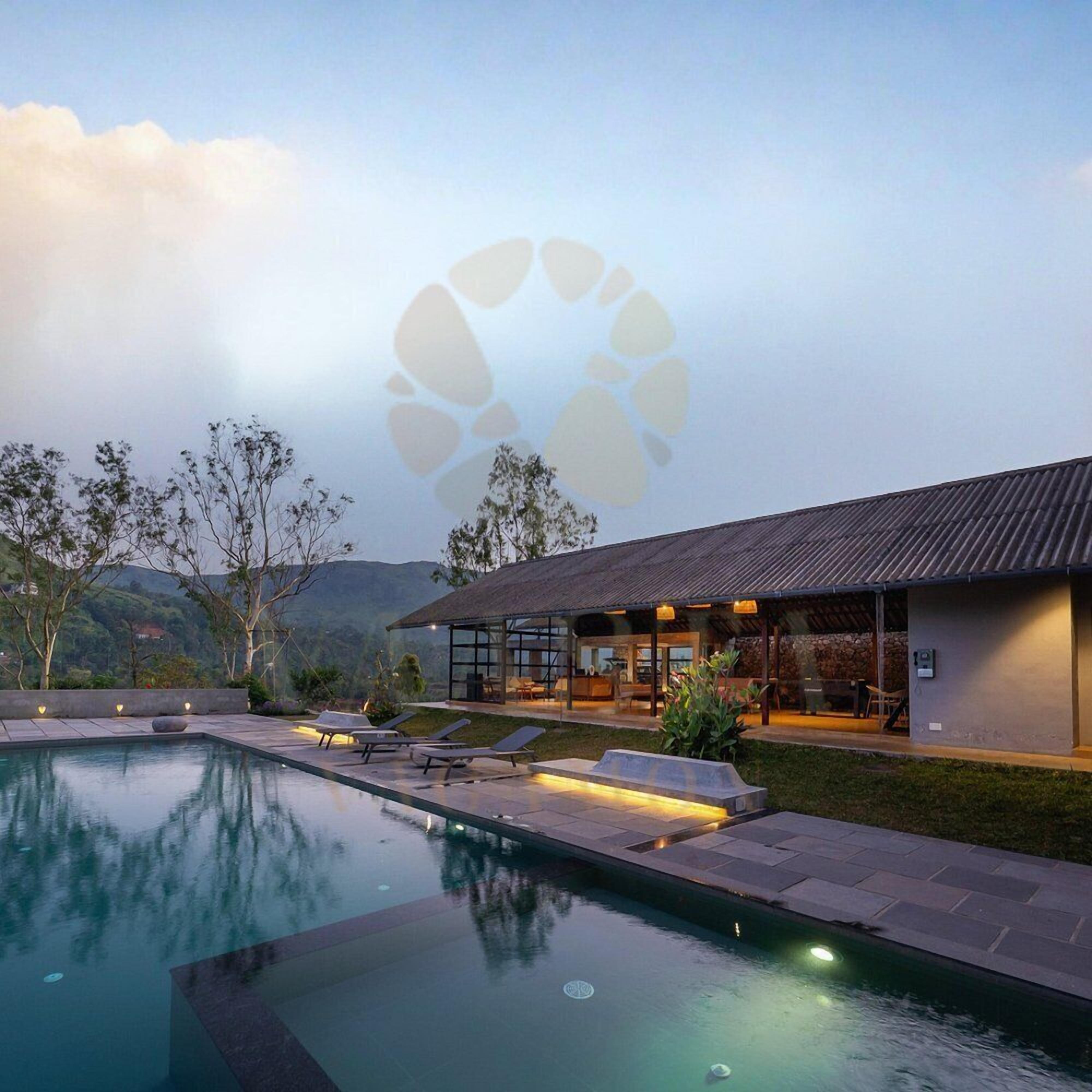 A modern outdoor pool area with lounge chairs, a covered seating area, and a view of the surrounding landscape.