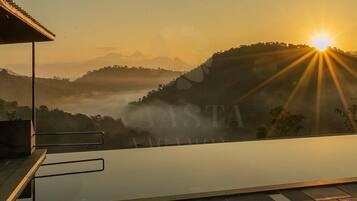 Une terrasse sur le toit offrant une vue sur le lever du soleil au-dessus d’un paysage vallonné.