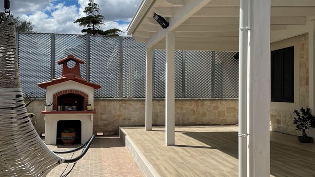 Un patio cubierto con chimenea de piedra, un pérgola y un espacio exterior cercado.