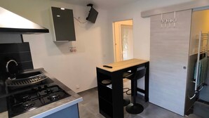 Une cuisine moderne équipée d’une cuisinière à gaz, d’une petite table à manger et d’une chaise noire.