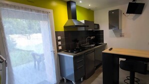 Une cuisine compacte équipée d’une cuisinière à gaz, d’un four à micro-ondes et d’un dosseret de carreaux noirs.