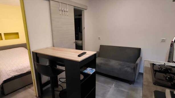 Une pièce de taille modeste comprenant un lit, une petite table avec une chaise, un canapé et un coin cuisine.