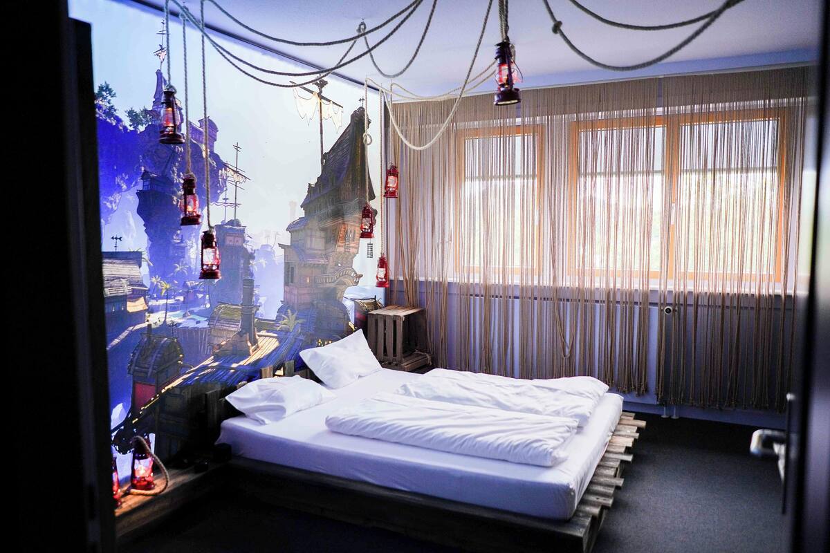 A hotel room with a large bed, a view of a cityscape, and a window with curtains.