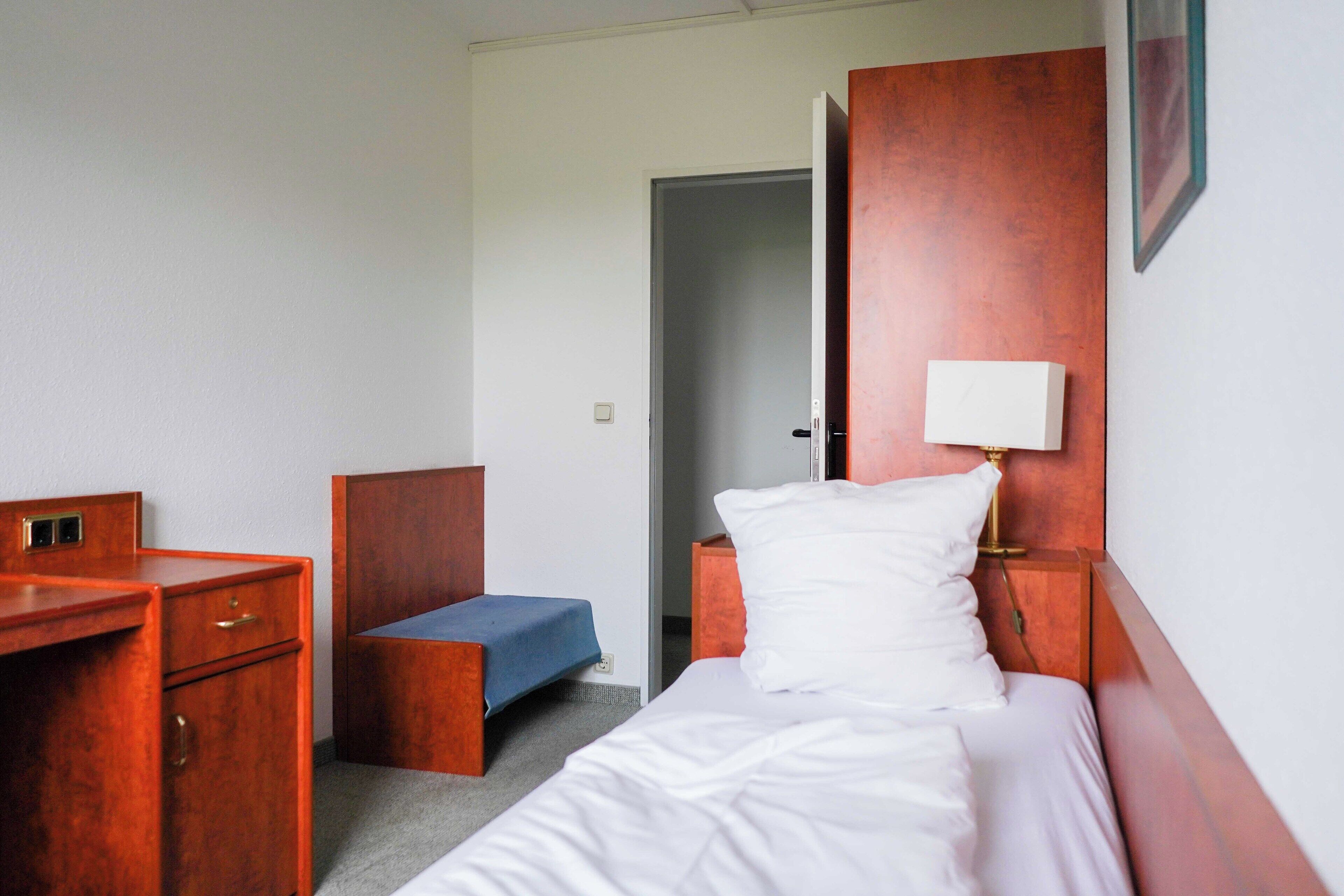 Een hotelkamer met een bed, een bureau, een stoel, een nachtkastje en een bedtafeltje.