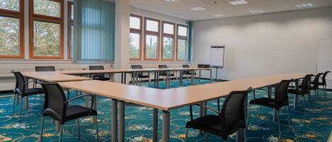 A conference room with a long table, chairs, a whiteboard, and large windows with blinds.