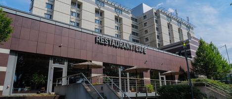 Un edificio de varios pisos con un letrero que dice "RESTAURANT CAFÉ" en la planta baja.