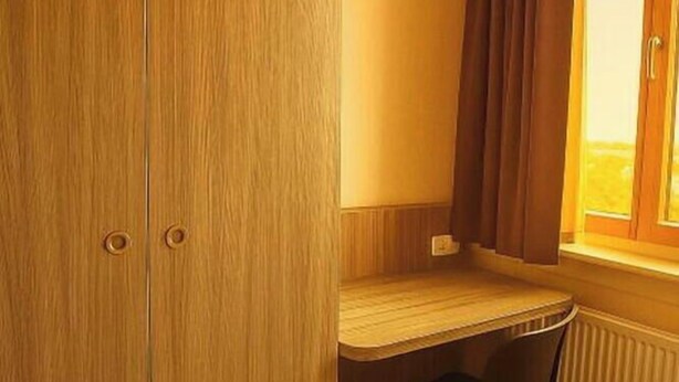 Una habitación con un armario de madera, un escritorio y un radiador.