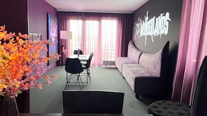 A modern hotel room with a dining area, a sofa, and a large screen displaying 'WONDERLANDS'.