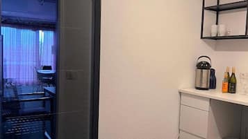 Una cocina moderna con puerta de vidrio de marco negro, un lavamanos, una encimera con botellas y un lámpara colgante.