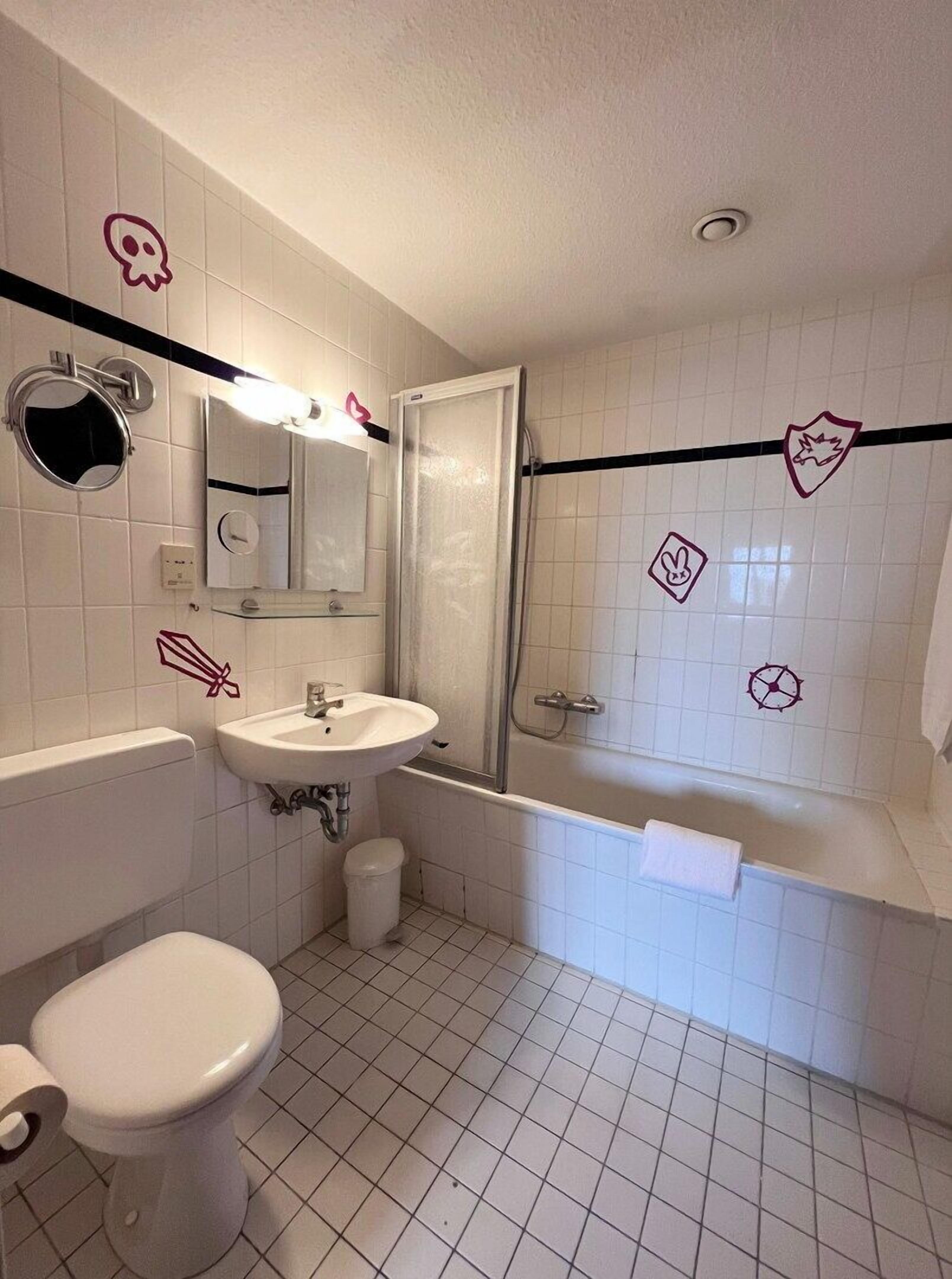 A bathroom with a toilet, sink, mirror, and shower.