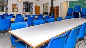 A classroom with blue chairs, a long table, and a chalkboard with 'Tillykke' written on it. - 6 Person Holiday Park Home in Laeso (Læsø)