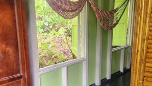 Une pièce avec un sol recouvert d’un tapis bleu tissé, une armoire en bois et un hamac suspendu au plafond.