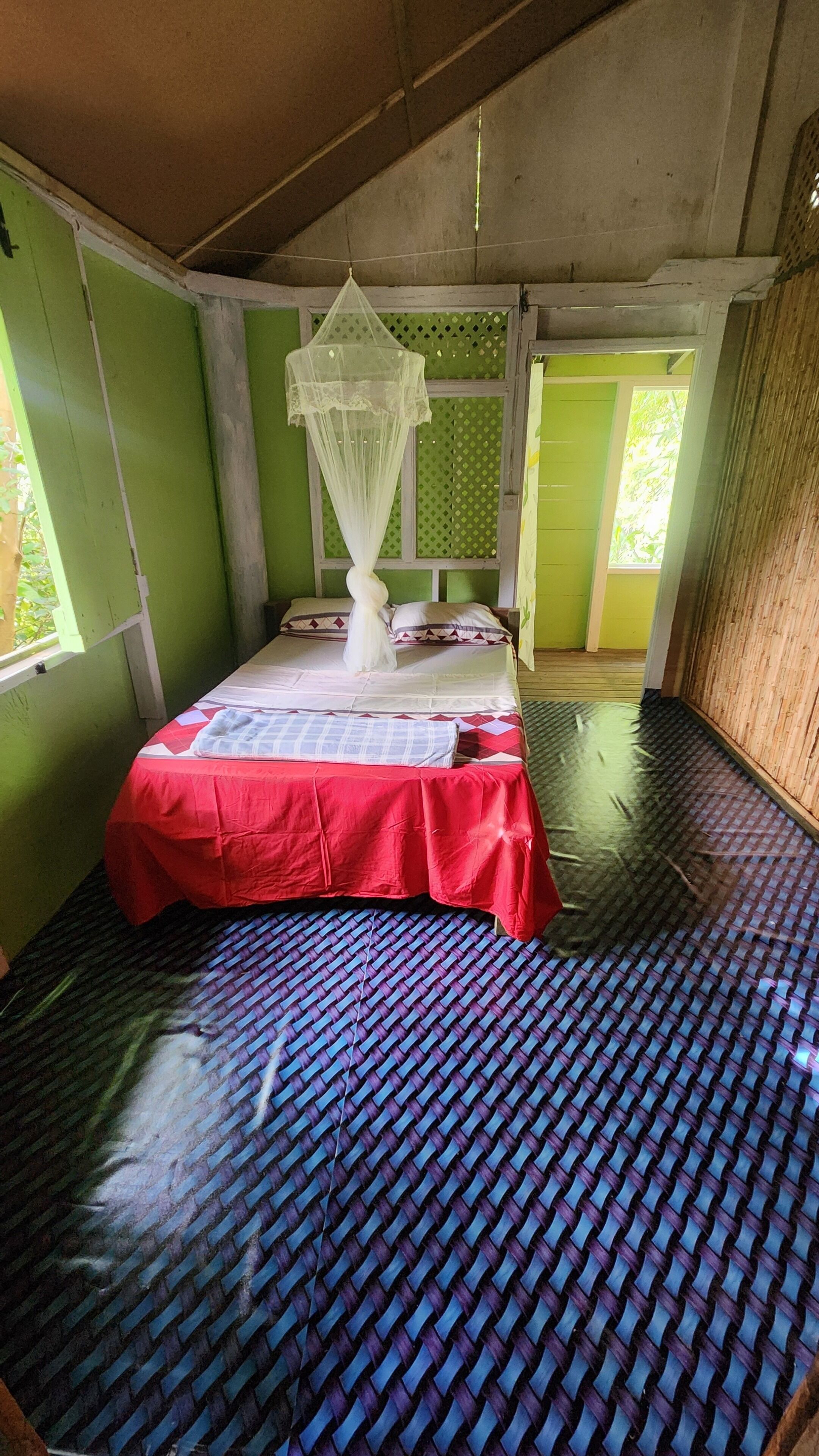 A room with a bed, a mosquito net, and a woven floor.