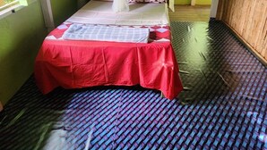 Une pièce avec un lit, une moustiquaire et un sol recouvert d’un tapis tissé.