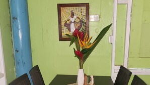 Une table à manger avec quatre chaises, un vase rempli de fleurs et un tableau encadré accroché au mur.