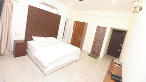 Ein Schlafzimmer mit Bett, Kleiderschrank, Schreibtisch und Telefon sowie einem Deckenventilator.
