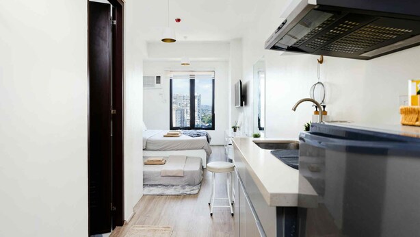 Cocina compacta con estufa integrada, un taburete pequeño y ventana con vistas a la ciudad.