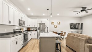 A modern kitchen with white cabinets, stainless steel appliances, and a marble island. - Charming 3BR Plover Townhome w/ Modern Comfort, Amenities & Style (Plover)