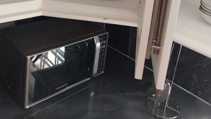 A kitchen with a black microwave, white cabinets, and a stainless steel sink. - Charming 2-bedroom apartment in Babonneau with WiFi, AC (Babonneau)