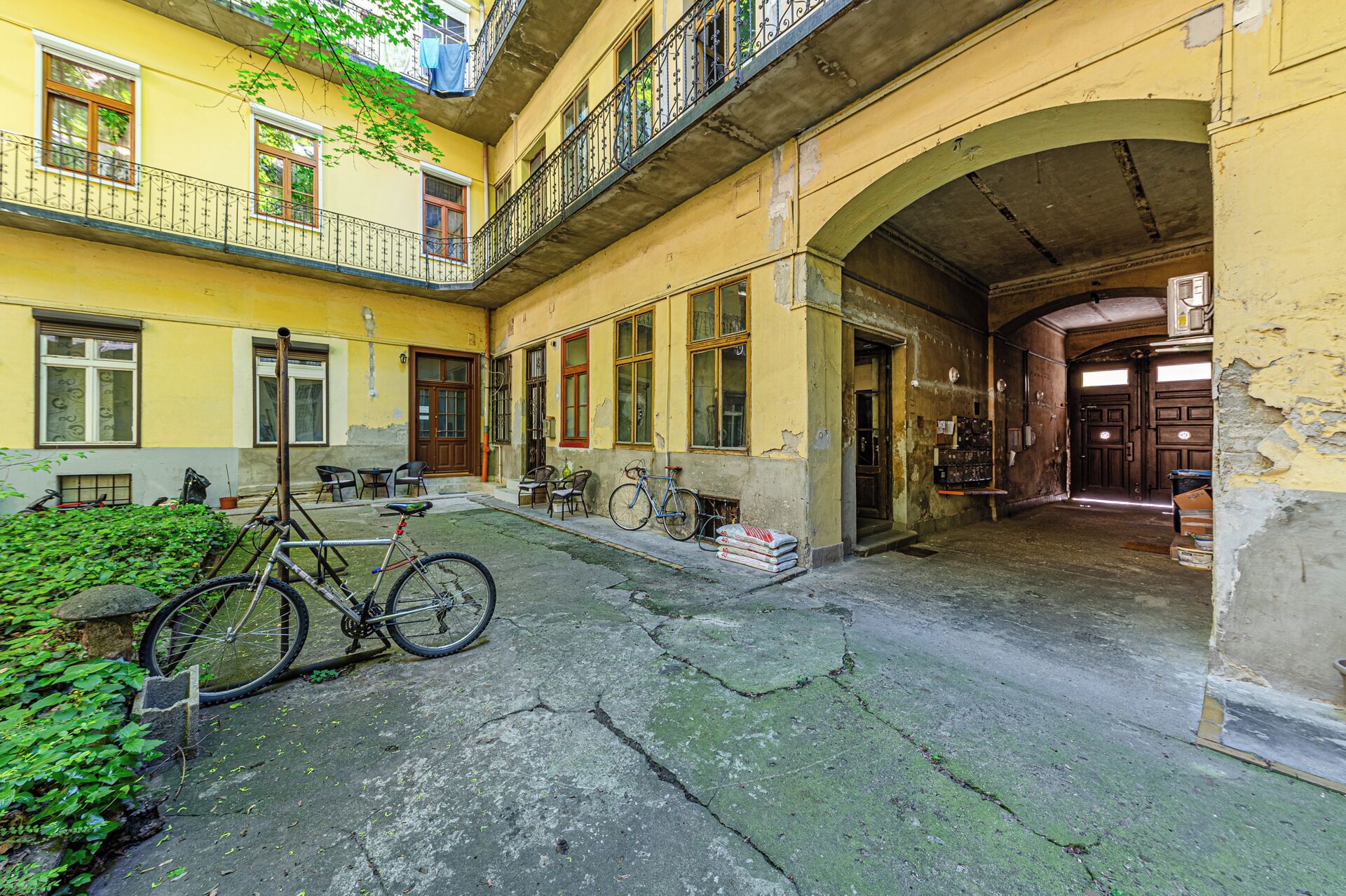Un patio con una bicicleta, asientos al aire libre y la entrada a un edificio.