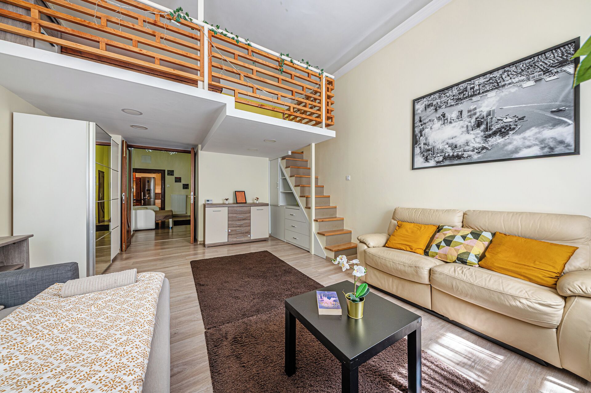 Eine moderne Wohnung mit Schlafgalerie, einem Wohnbereich inklusive Sofa und Couchtisch sowie einer Treppe, die zum oberen Stock führt.