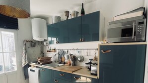 Una cucina compatta con mobili verde acqua, una lavastoviglie bianca, un forno a microonde e uno scaldabagno.