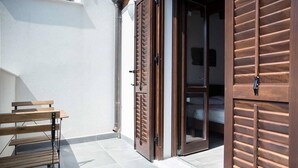 A hotel room with a sliding glass door, a wooden bench outside, and a tiled floor. - House Alley St. John (Palermo)