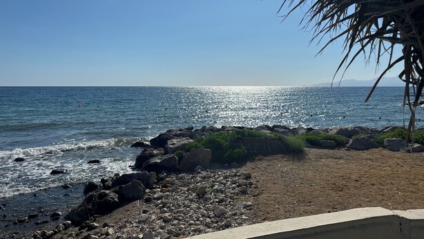 A beach with rocky shoreline, clear blue sky, and calm sea. - House Alley St. John (Palermo)