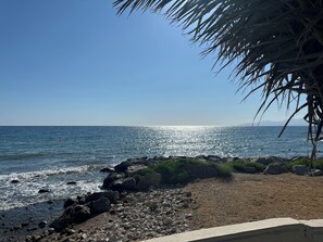 A beach with rocky shoreline, clear blue sky, and calm sea.