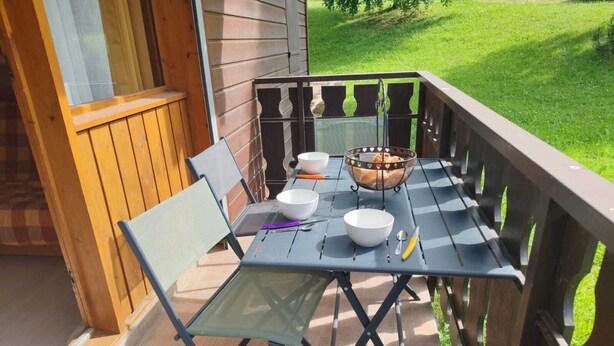 A wooden deck with a table and chairs, a basket of bread, and a bowl.